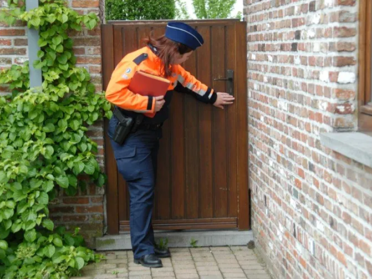 Politieagent die een poortje aan een woning bekijkt tijdens een vakantietoezicht.