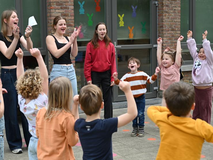 Animatoren en kinderen in een kring op speelpleinwerking 'de Schavuit'.