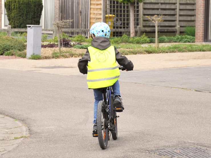 Kind met helm en fluohesje op een fiets
